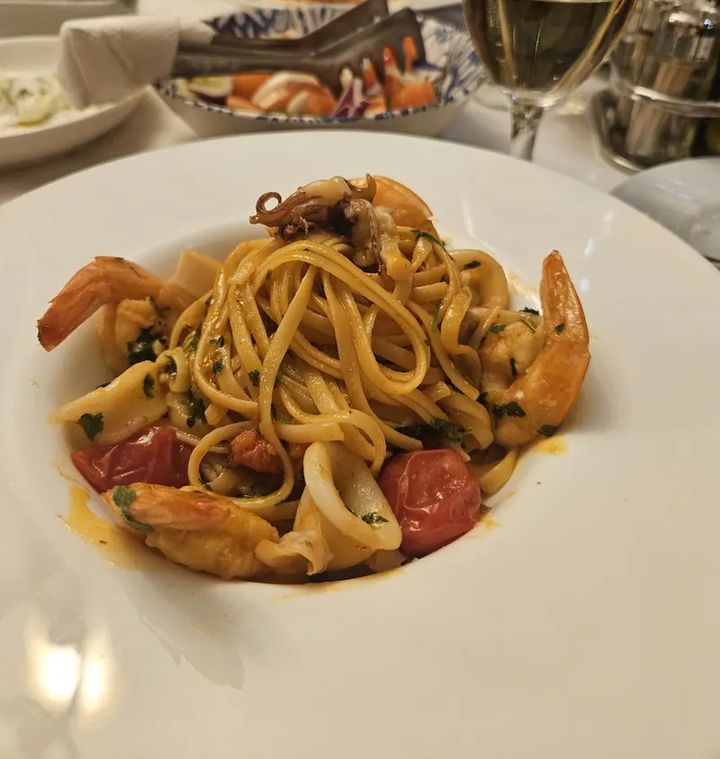 Linguine with prawns, squid and cherry tomatoes, with a glass of white wine