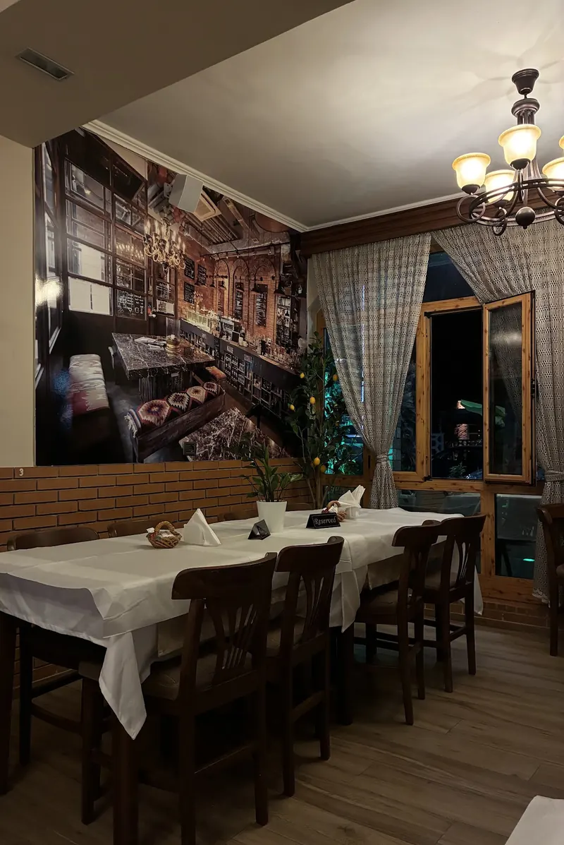 A long table set for guests by the window, under a chandelier, with a Reserved sign