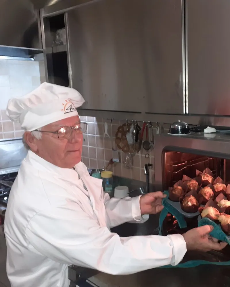 The chef of Restorant 4 stinët taking a tray of fresh muffins out of the oven