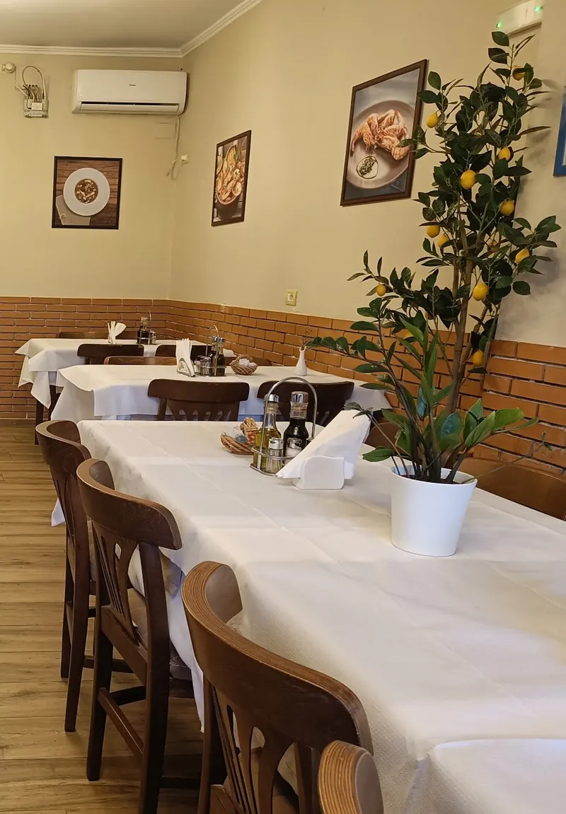 The dining room of Restorant 4 stinët: white tablecloths, wooden chairs, brick wainscot and a lemon tree